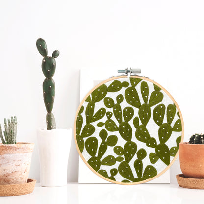 Prickly Pears Succulent Embroidery Hoop Art Displayed on a shelf with cactus plants