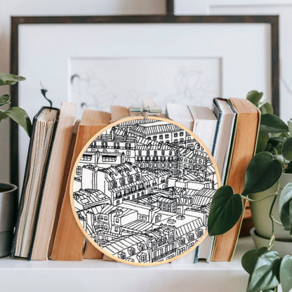 Rooftops of Paris France Embroidery Hoop Art Displayed on a Shelf with books